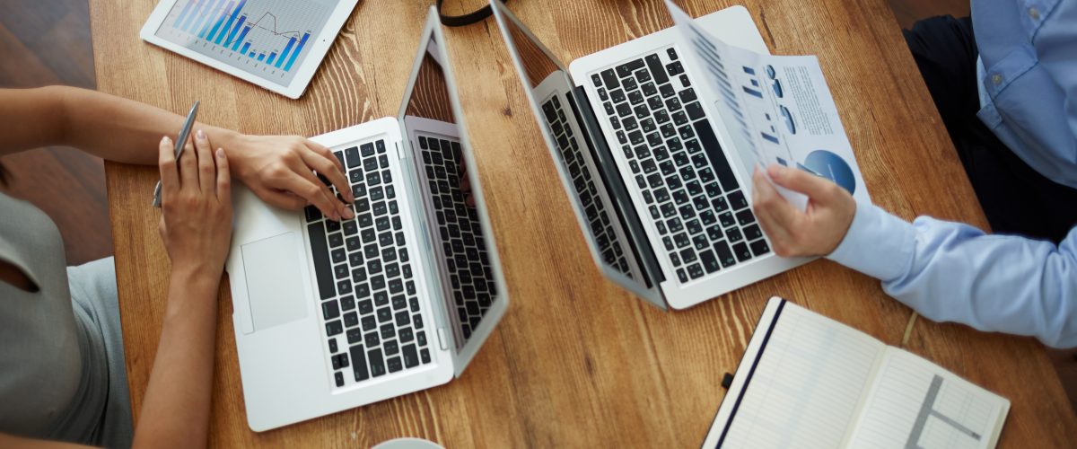 Analyzing data Workplace with gadgets, office supplies and two employees analyzing data